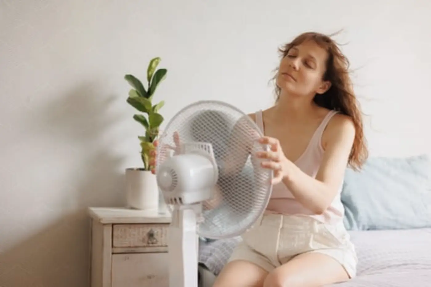 žena s mobilnou klimatizáciou a ventilátorom v spálni